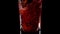 Trendy Nature Drink. Super slow motion shot of pouring pomegranate juice into a transparent glass against black