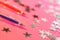 On a trendy pink background are silvery stars and two fountain pens: blue and red. The system of performance and grades in school