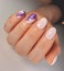 Trendy pink gel nail polish with an abstract purple fluid design. Manicure of soft pink color with a beautiful spreading pattern.