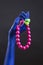 Trendy plastic jewelry. Blue woman`s hand with massive plastic Bracelet, beads and rings