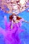 A trendy portrait of a beautiful girl in a purple dress posing and looking at the camera underwater at the bottom of an