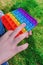 Trendy relaxing toy pop-it in boy& x27;s hands. A kid is holding anti stress rainbow fidget toy popit. Popular game for
