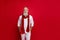 Trendy senior man santa like style holding hands in pockets wear warm knitted clothes isolated red background