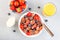 Trendy small chocolate cereal pancakes served with condensed milk, strawberry, blueberry and orange juice, in white bowl,