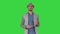 Trendy stylish positive cheerful man wearing casual shirt and sunhat walking and talking to camera on a Green Screen