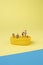 Trendy sunlight Summer scene made with miniature people on bright light blue and yellow background