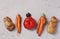 Trendy Ugly Organic Vegetables: potatoes, carrots, tomato and plum on gray background, ugly food concept, horizontal