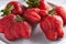 Trendy ugly strawberries in a plate on a light background