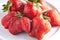 Trendy ugly strawberries in a plate on a light background