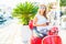 Trendy woman drinking takeaway coffee near her red moped on the