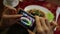 Trendy woman in a restaurant make photo of food with mobile phone camera for social network