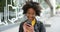 Trendy woman using her phone and smiling outside in an urban city. Funky and cool Afro American female browsing an