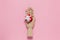 Trendy wooden mannequin hand holds small red gift box on pastel pink background, copy space, flat lay. March 8th, February 14th,