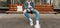 Trendy young man in youth stylish denim jacket in casual vintage jeans with fabric shopper sit on wooden bench at stop of public