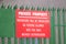 Trespassers will be prosecuted private property sign red on green fence