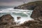 Trevose Head Lighthouse in North Cornwall with a stormy sky and waves crashing on the rocks makes a beautiful rugged landscape