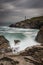 Trevose Head Lighthouse in North Cornwall with a stormy sky and waves crashing on the rocks makes a beautiful rugged landscape