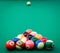 Triangle of colored pool billiard balls on green cloth