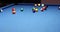 Triangle of multicolored pocket billiard balls and hit cue ball and scatter on blue table