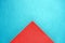 Triangle part of red paper napkin on blue cardboard background, copy space, top view