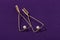 Triangle shape gold earrings with pearls on purple background