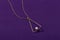 Triangle shape gold pendant necklace with pearl on purple background