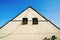 Triangular facade of a rural house with two square symmetrical windows