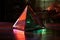 triangular glass prism reflecting vibrant colors on dark table