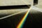 Triangular Prism dispersing sun beam splitting into a spectrum on wooden background