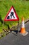Triangular red and white road hazard warning sign with hi vis rubber traffic cone marking road maintenance works in County Down in