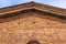 Triangular roof of an old building of orange bricks against a blue sky