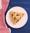 Triangular slice of baked cherry pie on a pink round plate