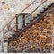 Triangular stack of firewood under a wooden stair in a rustic country house