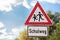 A triangular warning sign. Attention, children on the way to school.
