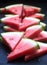 Triangular watermelon slices with seeds on a black concrete background