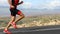 Triathlete man running in triathlon suit training for ironman running up hill. Close up of legs and shoes. Male runner
