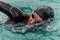 A triathlete in a professional swimming suit trains on the river while preparing for Olympic swimming