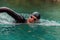 A triathlete in a professional swimming suit trains on the river while preparing for Olympic swimming