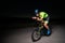 A triathlete rides his bike in the darkness of night, pushing himself to prepare for a marathon. The contrast