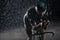 Triathlon athlete riding bike fast on rainy night