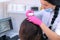 Trichologist examines woman patient hairs using computer trichoscopy in clinic.