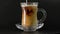 A trickle of milk is poured into the hot steaming coffee. Transparent glass,black coffee in Turkish. Hot drink on a dark