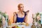 Tricky lady with colorful makeup sitting behind table and eating felt shoe