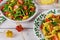 Tricolor rotini pasta, tomato, in christmas bowl with green salad on white table