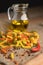 Tricolor spiral pasta with spices on a dark wooden table.