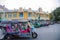 A tricycle tuk-tuk waits for tourists in front of an ancient yellow building in Bangkok