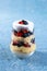 Trifle dessert with berries and cream on blue background