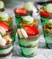 Trifles in plastic glasses with fresh fruit and cream.