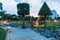 Trimmed trees and bench in the park and yellow bright lanterns in the evening