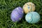 Trio of colorful Easter eggs laying in bright green grass.